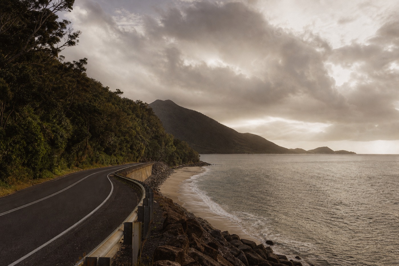 The Captain Cook Highway curving along the tropical coast between rainforest hills and the Coral Sea at dusk